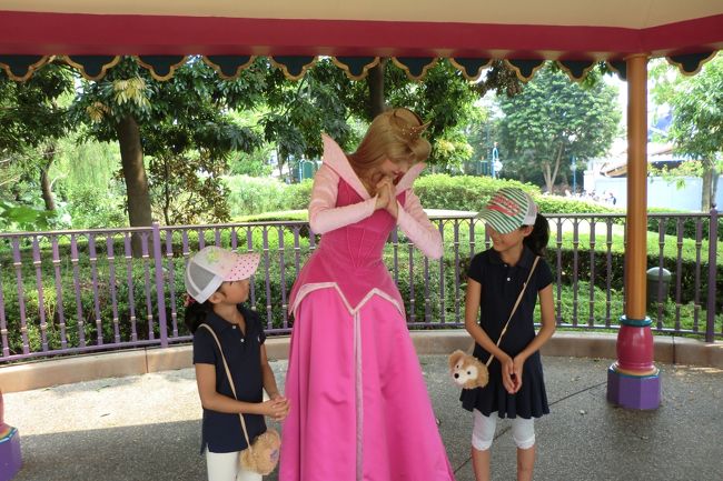 ＜２日目＞<br /><br />今日は香港ディズニーランドを訪れます。<br /><br />ランドにつくと、みなさん一斉に傘（雨傘）を日よけ代わりに開いてました。そうでもしないと、日光に「襲われる」感じになります。我が家も小型の日傘兼雨傘を持参してましたが、あるとないとではだいぶ違いました。<br /><br />香港ディズニーでは、キャラクターの出没時間が長く、あちこちでグリーティングをしていました。<br />　オーロラ姫にプリンセスポーズを習ったり・・・