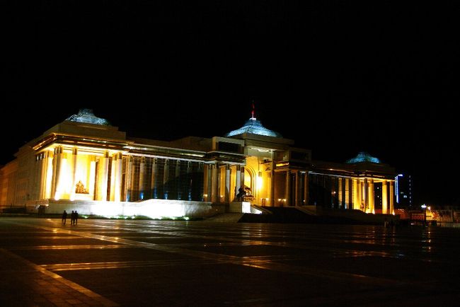 　チンギス･ハーン空港は，バゲージレーンが一つしかない小さな空港なのですが，やたら金属探知機があり，入国手続はゆっくりだし，優先のはずの手荷物が何故か一番最後（ロスバケか？と心配）になり，迎えに来てくれたＳ教授と現地ガイドのエリカさん（男性）をずいぶんお待たせしてしまいました。急ぎ足で市内に移動したため空港の写真はありません。<br />　Ｓ教授の計らいで，ホテルに入る前に”不思議な装飾感覚の街”を象徴するスフバートル広場に来ました。すでに午前０時ですが，政府宮殿はまだライトアップされています。