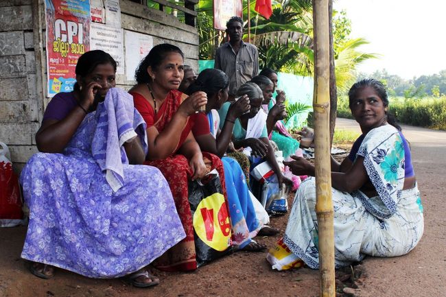 出勤のバスを待つ女の人たち。ビニールバッグが必須アイテム。