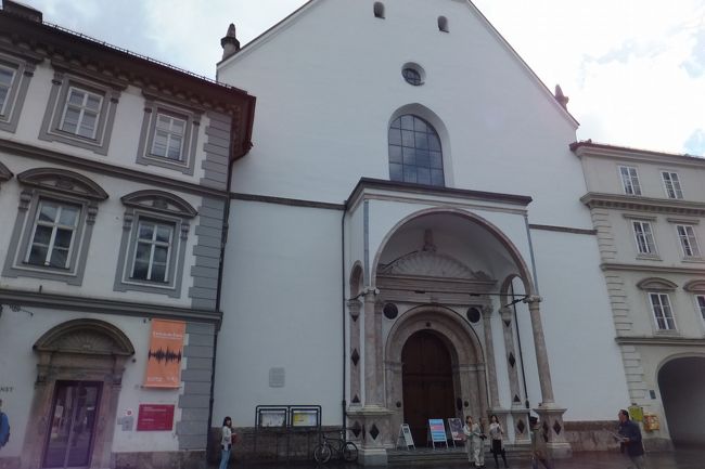 で、王宮まで戻ってきました。王宮内の博物館に入ってみます。インスブルックカード有効。正直特に見るものはなかったが、大広間だけは見ものです。フレスコ画？が立体に見えます。あと壁にかかる肖像画のほとんどがマリアテレジアで、ちょっとだけマクシミリアン1世があります。ちょっとどうかな。ちなみに写真撮影は禁止でした。<br />写真は宮廷教会正面とチロル民族博物館の入口です。宮廷教会のチケットもこちらで購入します。インスブルックカード有効。インスブルックカードを見せると両方のチケットを渡してくれました。チロル民族博物館はとくに見るものはなかった。