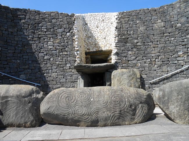 ニューグレンジ<br /><br />入口には渦巻き模様と菱形紋が彫刻された巨大な石の平板<br /><br />ガイドとともに中に入ります。<br /><br />塚の差し渡しの3分の１ほどの長い通路の先端に十字型の部屋がありました。<br /><br />