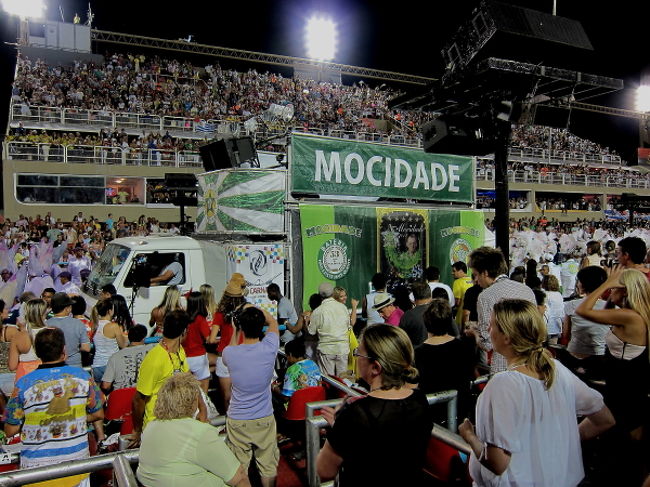 4番目のチーム「Mocidate」が登場することには深夜0時を回ってきました。座席ですが、野球観戦のスタンドのような席、真ん中へんに見える個室のようなところなど、種類があるようです。企業・グループなどの貸切スペースでは、サンバの衣装のお姉さんも登場してパーティーをしているところもありました。