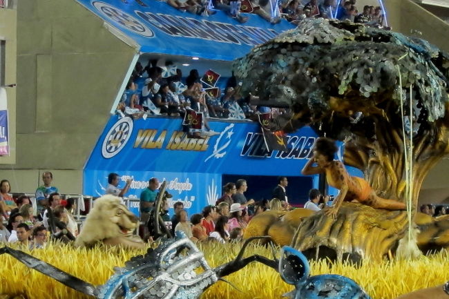 いよいよ今日の最終チーム「Vila Isabel」の登場。このチーム、去年は5位でしたが、今年は堂々の3位に！私達のグループは、この最終チームのラストまで見ていると、帰りの混雑が怖いので、ガイドさんのアドバイスもありバスを呼んでもらい、帰り支度を始めたのですが、このチームの素晴らしさに釘付けになってしまいました。<br />これは先頭のパフォーマンスですが、黄色い草原の中からジャッカルや他の動物が顔を出し、その人たちが山車を降りて踊ったりとつかみもすごかったです。