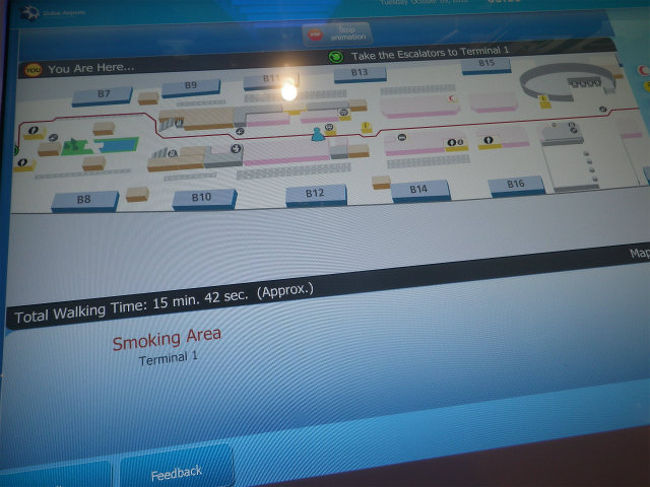 早速スモーキング・ルームを、タッチパネル表示の大画面案内板で探しました。<br />ナント、この広い空港に一箇所しかない。<br /><br />この案内表示、自分の居る位置から、画面中央の青い人形マークが目的地に向かってトコトコ移動していきます。この画面は２画面目です。喫煙場所は次の３画面目。<br />乗り換えゲートから入って来たのも、乗るゲートもこの”Ｂｘｘ”のターミナル３なのに、案内では”Ｃｘｘ”ゲートの近くと出て、別のターミナル１まで移動することに。何しろ予想歩行時間１５分４２秒ですから、行くの大変そう。