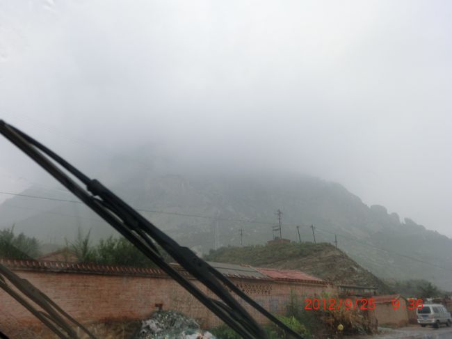 結局、鶏鳴山は雨に隠れ最後まで姿を見せず <br /><br />この写真が一番見えている <br /><br /><br /><br />/////////////////////////////////////////////<br /><br />■鶏鳴驛へ <br /><br />雨が降り止まぬままだったが今回の旅で期待していた鶏鳴驛に向かった。来る前に写真などで見た鶏鳴駅は、城壁に四方を囲まれた姿を今に留める魅力有る所だった。１９００年に義和団の乱の時、西太后が西安に逃げる途中ここで一泊している。 <br /><br />｢人民網日本語版｣2008年3月18日 <br /><br />http://japanese.beijingreview.com.cn/ly/txt/2008-03/19/content_105801.htm <br /><br />////////////////////<br />中国に現存する最大の宿場町――鶏鳴駅。2年近くかかった修復作業が完了し、北京周辺の独特な観光スポットとしてこのほど一般開放された。 <br /><br />宿場町は昔、文書を運ぶ伝令が馬を交換したり、休息したりする場所だった。 鶏鳴駅は河北省張家口市の懐来県にある鶏鳴山の麓に位置し、北京からは100キロ余り離れている。元の時代以降、清王朝が1913年に全国の宿場を撤廃して、郵政局を設立するまで、北京と西北地方を結ぶ中継地としての役割を果たした。 <br /><br />鶏鳴駅は他に現存する宿場と同様、高さ11メートルでほぼ正方形をした2キロの城壁に囲まれている。城内にはなお17軒の寺院と馬小屋、練兵場、商店などが残っている。中国国内でも保存状態が最もよく、最大の規模を誇る宿場だ。 <br /><br />｢人民網日本語版｣2008年3月18日<br />//////////////////// <br /><br />修復され残念ながら古さを感じない城壁で囲まれた鶏鳴驛に９時４０分過ぎに到着した。東門の城壁には「鶏鳴山驛」と掲示があり、門の傍には「鶏鳴驛」との大きな碑が立っている。「鶏鳴山驛」と「鶏鳴驛」どっちでも構わないのということなのだろう。 <br /><br />大人は門票６０元だったが、売り場の小姐が私を見て向こうから「６０歳以上は３０元」と声をかけてくれた。「我是６２歳」というと身分証を見せろとも何も言わず「３０元」にしてくれた。「へぇ〜、自己申告でＯＫなんか？」と驚くやら、「やっぱし６０歳以上に見えるんや」とがっくりするやら気持ちは複雑だった。 <br /><br />城内の予備知識は、１９００年の義和団事件の際、西太后が西安に逃げる道中に一泊した家が残っているということだけで他は何も知らず。まず城壁に登って城内の風景を見た。周囲が城壁で囲まれ平屋の家屋が立ち並び、人の気配も感じず静かだった。残念なことに小雨と霧で目の前に聳えているはずの鶏鳴山もかすかに山裾がぼんやりみえるだけで、ほとんど姿を隠していた。 <br /><br />晴れていたら随分景色も違ったと思う。とりあえず城壁の上を一周回ろうと、時計と反対周りで歩いた。観光バスで来ている中国人観光客が、城壁の上をちらほら歩いていた。城内の家屋は朱か黒かの屋根瓦で色の統一感もあり、城壁から見下ろす城内はそれなりの雰囲気はあるが、人の気配がなく静かだ。写真を撮りながら、ゆっくり歩いて２キロの城壁を３０分ちょっとで一周した。 <br /><br />そこから下に降りて城内を散策。放し飼いの犬に吼えられるのが嫌だったけど、そんなこともなく、路地から路地へと適当に歩く。土産物屋のような家もあったが、今日は雨だし観光客も少ないのか、人の姿少なく、時折屋内から話し声が聞こえるので人はいるのだろうが、賑やかさとは一切無縁の鶏鳴驛だった。 <br /><br />そして唯一の予備知識があった、西太后の宿泊所を見つけて入っていった。狭い入り口の上に「一九零零年、慈禧西行時、曾在此留宿一宿」「１９００年　慈禧（Cixi　西太后）が西安行く時、一泊した宿」との看板があった。人一人しか通れない狭い路地の置くに四合院があり、そこが西太后の宿のようだ。慈禧太后（Cixi Taihou ツーシー・タイホウ） <br /><br />何故ここが宿になったのか？他と変わらぬ小さな四合院の一棟に西太后・光緒帝の掛け軸が掲げてあり、それらしき物が一応並べてあるが、誰も人はいなく価値有る物は置いてないというのは見て分る。あの西太后がここに？ホンマかいなと思うが、別段真偽を問うつもりはない。それより、こんな所だからこそ、逃避行での宿として信憑性を感じる。この四合院に宿泊したのは義和団事件で八ヶ国連合が北京に迫った時なので、オンドル不要の８月の暑い時期だったろう。 <br /><br />新品の偽物展示家屋より余程雰囲気はある。このままで置いて欲しい。今回帰国後、ＮＨＫテレビドラマ、「蒼穹の昴」：２５話：ＤＶＤ８枚を借りて三日で見終わった。ドラマは見応えがあり、当時の紫禁城内の人間模様が良く分かり面白かった。 <br /><br />「蒼穹の昴」では、権力の頂点で一国を私物化し、贅沢三昧に慣れた西太后が、鶏鳴驛の狭い路地を歩き、あの部屋に一泊したとは・・・。その時、光緒帝（清国：第１１代皇帝）も一緒に同行していた。光緒帝は、西太后（享年７３歳）の死ぬ一日前に毒殺（満３７歳）されている。光緒帝の母親は西太后の妹。１９００年に西安に逃げた西太后も２年後に紫禁城に戻りまた権力の座に着いた。 <br /><br />城内はこれからも観光化されて行くのか、新しい昔風の建物が何棟も作られている。どことも同じパターンで、出来上がりは想像に容易い。雨降りだからか往来に人の姿も少なく活気はない。何せ小さな村なので静かだった。きっと晴天の時なら、あちこちで地元の年寄りたちが椅子に座って道行く人を眺めていたり、子供たちが遊ぶ光景もあるのだろうが、この雨ではしょうがない。 <br /><br />鶏鳴山もとうとう最後まで姿を見せず、１時間２０分くらいの散策で鶏鳴驛を去る。感想を一言で言えば、ここも修復下手でがっかりだった。 <br /><br /><br /><br /><br />