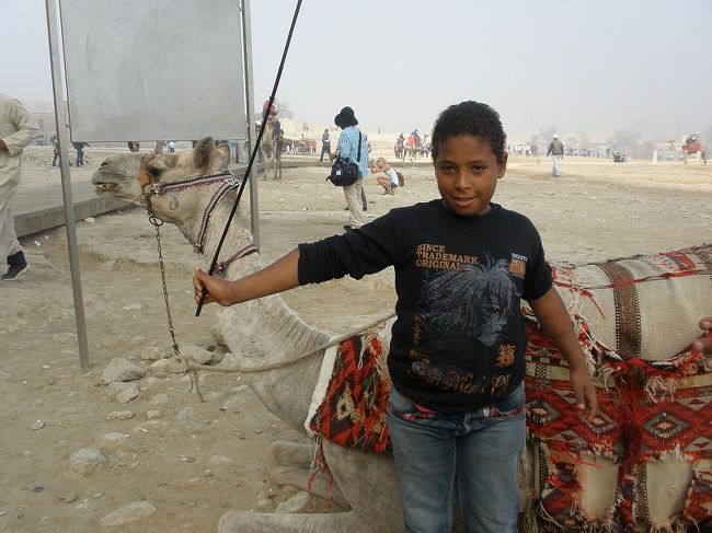 エ「ダメ！金はないよ！アメちゃんならあげるよ。」 <br />小「アメなんかいらねー！金よこせ！ワンダラ！ワンダラ！！」 <br />エ「金はねぇつってんだろ！アメ持ってとっとと消えろ！」 <br />小「いいから金よこせってんだよ！じゃ、そのＧショックよこせ！」 <br />エ「ふざけんなバカヤロウ！誰がオマエにくれてやるか！」 <br />と、お互いカタコトの英語でやりあうが、どちらも引かず <br />気がつくと、小僧が増えていやがる。 <br />ふっと　周りを見たら、ラクダに乗せられ写真を撮ってるツアー仲間が目に入った。 <br />あぁぁ、あの人はいくらせびられるんだろ・・・と心配になった。 <br />が、その前に自分の事で精一杯 <br />いい加減もういいやと、持ってたアメをカバンに仕舞おうとすると <br />小「じゃ、アメでいいよ」と。 <br />最初からそーすりゃいいんだよと　その小僧に2コあげると、「兄ちゃんの分よこせ」と。 <br />あ”〜！もう <br />すると、関係のない小僧までも「アメくれ！」と <br />振り払いたい一心で、そいつにもあげると、「父ちゃんの分よこせ」だと <br />気がつくと、大人のおっさんまで「アメちゃん！アメちゃん！」と手を出してる。 <br />おめーは関係ねーだろ！ <br />と思いつつも、早くバスに逃げ込みたいので、あげてしまった。 <br />でも、最後まで着いてきた関係のない小僧が　ちっちゃいスカラベをくれた。 <br />疲れた・・・ <br />