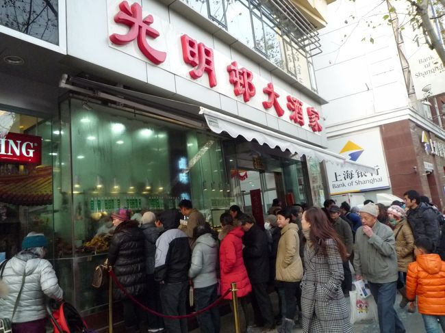 ホテルから淮海路を東へ行くと、人民たちの大行列が！<br />『光明邨大酒家』<br />淮海中路と成都南路の交差点近く、淮海中路588号<br /><br />行列の元を確認すると、豚鶏魚などの茶系惣菜の列と、肉月餅の列との2本に分かれていることが判明。<br />