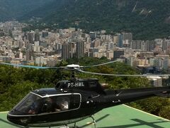 ポン・ジ・アスーカルという日本人にはそれはもう発音しずらい名前の岩への登頂を試みるならまず第一ゴンドラで第一の岩によじ登り一旦途中下車し再び第二ゴンドラに乗り換える必要があります。

でも..でもね...第二ゴンドラがそれはもうすごい行列なんです。
真夏の日差しもたいそう強いし..日陰もないこの場所で...幾ら行列に慣れている大和民族でも流石に長時間立って待ってられねぇ...こんなところで..。

根性や我慢心がもう１mmリットルも残っていない我々は、即岩登りを断念しました。

う〜っっ暑い..誰か水をくれ....。

呆然としている我々の前にボーっと佇んでいるヘリコプターを突然連れが発見！

その足で冷房の効いた事務所に飛び込みカウンターでつたない外国語で汗をかきながら一生懸命、ｺﾐｭﾆｹｰｼｮﾝを取る。

我々野郎共３人２５分の遊覧飛行でR$360(約17,000円)という値段。

｢これ、いいんじゃな〜いの〜！｣。

気の短い我々日本人は即決で乗込み、リオの街を一望する事に。

教訓：旅先の金は出し惜しむな。困った時はお金で解決。