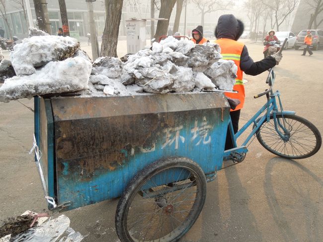 通りの凍った雪の塊を集めてる人がいました。