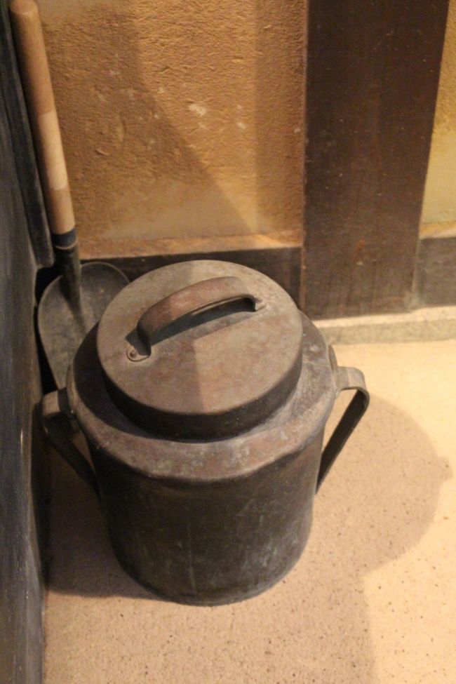 カマドの横に置かれた銅製の炭壺。<br /><br />これは、カマドから出た残り火を入れておく道具で、中の酸素がなくなると消し炭になります。<br /><br />炭壺の使い方を説明できる私は、はたして何歳でしょうか？