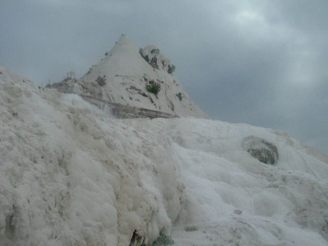 ６時前に宿を出て、石灰棚へ向かう。昨日下見に行った時上の方にまで踏み分け道がついていたからだ。まずは墳水塔のような岩へ目指す。道はところどころに続いているが、自然に棚をよじ登ったり、せせらぎを横切らなくてはいけない。石灰棚を直登するとヒエラポリスであった。石棺が石灰棚に飲み込まれてしまい、下から見上げることができた。<br /><br />