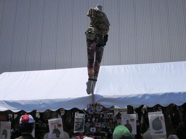 先に会場を一周してみようと思い、右のほうへ入っていくと、露店ブースが。<br /><br />ストラップや戦闘機の模型やらのグッズを販売するコーナーは超人気。<br />ブルーインパルスはやっぱり人気なんですね〜、私は名前ぐらいしか知らないけど(笑)<br /><br />その隣で見つけたのが、ミリタリーウェアって言うんでしたっけ？<br />Tシャツとかジャケットとかを売ってるお店がありました。<br />このマネキンで果たして売り上げアップできるのか(笑)