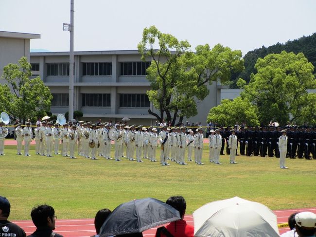 露店を通りすぎて奥のほうへ進むと、中央訓練場に出ます。<br />ここが会場の右奥（入口から見て）になります。<br /><br />ここでは、9:50から「観閲式訓練」が行われていて、私は10時過ぎに到着する予定だったので、途中から見ようと思っていたのですが、バスを1台見送ったこともあり、諦めていました。<br /><br />ところが、なぜか予定を押していて、終了予定時刻の10:40を過ぎても終わっていませんでした。<br />もう戦闘機が飛ぶ時間（10:50〜11時）になってるんだけどな〜。<br /><br />白い服を着てるのは音楽隊です。
