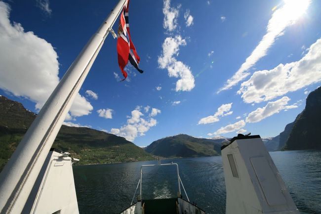 ノルウェーの旗をなびかせて、船は進みます<br /><br />青い空・白い雲　そしてフィヨルドがついてきます