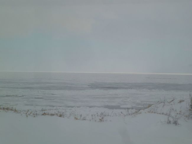 吹雪の車窓から、オホーツク海が垣間見える。<br />奥に白く見えるのが流氷。