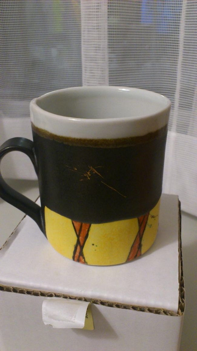 これを買ってしまったのです（写真は夜ホテルの部屋で<br />とったもの）。<br />「優しい時間」というドラマで使われたデザイン。<br />「拓郎マグカップ」です。<br />ご存じの方は見ただけでわかると思いますが・・・<br />やっぱり買うならこれですねぇ〜<br />（旅行から戻ってきてドラマを見直したのですが、<br />そのほかのカップもいくつかドラマで使われてたようでした）