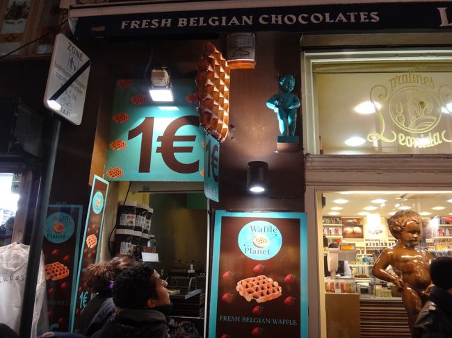 ベルギー・ブリュッセル【Leonidas】（レオニダス）<br /><br />レオニダスでワッフルを販売しています。<br />つい先程行ったグラン・サブロン広場にある<br />レオニダスには、ワッフルは販売されていませんでした。<br />エチューブ通りにあるこの店舗だけ？<br /><br />何と店頭には「1ユーロ」の看板が掲げられています。<br />1個1ユーロのワッフルが販売されているようですが、<br />トッピングする前のワッフルの生地の値段が<br />1ユーロということなのでしょうか？