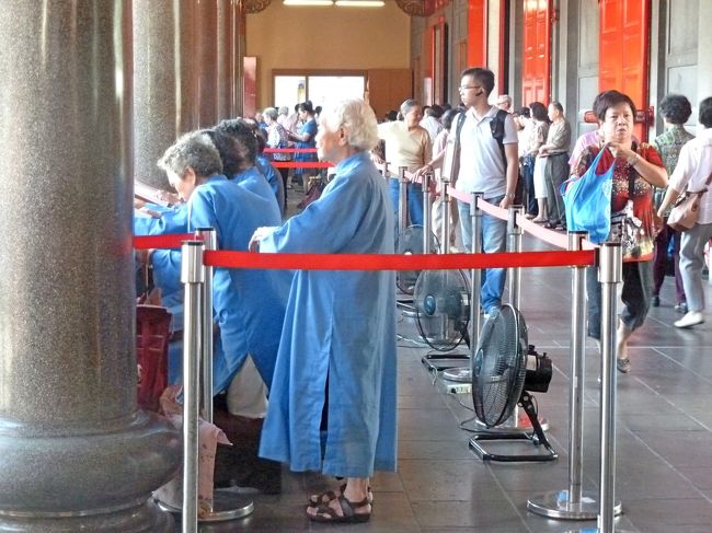 青い服を着た人たちが合掌のようにお経（かなあ）を読む