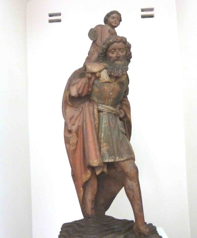 クリストフォロスはキリスト教伝道のために、無償で人々を背負って急な川を渡っていました。<br />ある日、小さな男の子が川を渡りたいとやって来ました。<br />お安い御用とその子を担いで渡り始めたのは良かったが、見る見るうちに異様な重さになった。<br /><br />この子はイエス･キリストの仮の姿で、全世界の人々の罪を一身に背負っていたので異様に重かったのです。<br />やっとのことで渡りきったクリストフォロスは、聖人の称を名乗ることになったそうです。<br /><br />