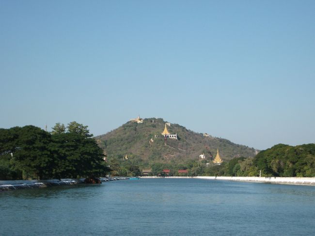 オールド・パレスのお堀からマンダレーヒルの眺め<br /><br />ここからゲストハウスへ戻るときに歩いていったために飛行機の出発時間まであと2時間しかない。<br />ゲストハウスのスタッフから、1時間では空港に着かない。<br />そこで1時間で着けるタクシーを手配するが$25かかると言われて、選択の余地がないのでこのタクシー(たぶんタクシーではない)で何とか一時間前に到着。<br />が、出発時間5:20pmが7pmへ変更されていた。<br />そういえば、ミャンマーの国内線は出発の遅れ、キャンセルは日常茶飯事と書いてあった。<br />事前にゲストハウスで航空会社へ再確認の連絡をしてもらったが繋がらなかったって言っていたので、もし事前に情報を入手していればこんな無駄はなかった。<br />まあ、キャンセルじゃなくて良かった。