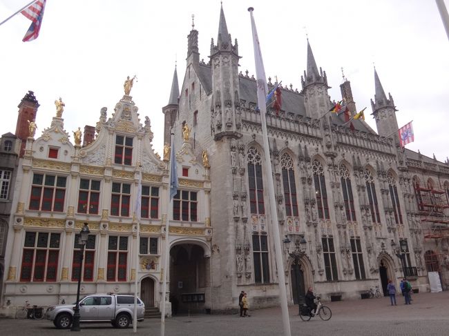 ベルギー・ブルージュ<br />『公文書館（自由ブルージュ博物館）』<br />（Civiele Griffie（Museum van het Brugge Vrije））<br /><br />旧裁判所と市庁舎の間に挟まれた感じで建っている<br />市庁舎に隣接した写真の左側の建物は、<br />1537年に完成したルネサンス様式の『公文書館』です。<br /><br />内部は、カール5世を称える目的で造られた<br />自由ブルージュ博物館になっています。<br /><br />白塗りの壁に金箔の装飾、屋根にも金箔の銅像が<br />立ち並び、小さい建物ながらも目立っています。<br /><br />公文書館の建物の右側には、通り抜けできる<br />通用門があり、ダイヴァー運河（Dijver）へ<br />抜けることが出来ます。