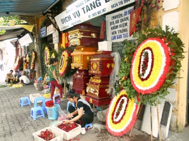 偶然、葬儀屋さんの集まる通りへさしかかりました。<br />棺らしきものも、積み重ねられていますね。<br /><br />丸い形をしたものは、葬儀用の花輪のようです。