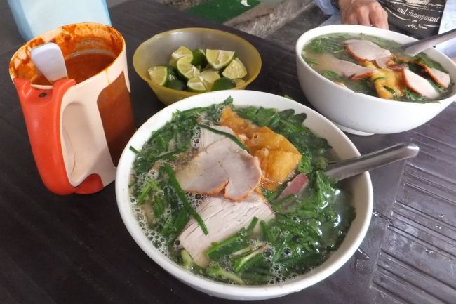 こちらが、その<br />ミー・ヴァン・タンです。<br /><br />ミーというのはベトナムでは中華麺のことで<br />ヴァン・タンというのはいわゆる「わんたん」です。<br /><br />麺は、この下に隠れていますが<br />博多ラーメンのようなストレート麺で、少しかため。<br /><br />でも、変わっていたのは<br />私たちが想像するようなわんたんとは違って<br />大きな三角揚げのようなものがあって、<br />その中心に牛肉の挽肉がありました。<br /><br />そのほかに、ほとんど皮のひらひらのないシュウマイのようなワンタン。<br />これは、私は豚肉だと思うんだけど、コショウがきいてました。<br /><br />それから、チャーシューのようなものや<br />豚レバーも入っていました。<br /><br />そして極め付けは、トッピングの緑の野菜。<br />なんと、春菊だったんです。<br /><br />私は麺は食べなかったけど<br />三角揚げのワンタンもスープが染みてて<br />とってもおいしかったですよ。