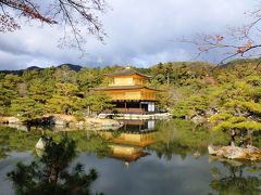 船岡山から金閣寺へは道もなだらかに下っていて、アシスト機能がなくてもなめらかに自転車はすすみます。

逆に速度が上がってしまうので、歩行者に気を付けなければなりません。

こうして高校時代における修学旅行以来の金閣寺を訪れたのですが、日本でも五本の指に入る有名な観光地とあって、どこへ行っても人だらけ。

金閣寺の、この世のものとは思えない程の神々しく妖しく華やかな景観を存分に楽しむには、目にも耳にも招かれざる情報が飛び込んで来すぎでした。

よく知られたことですが、金閣寺の正式な名称は鹿苑寺。

金閣は金色に輝く舎利殿につけられた名前なのですが、いつの間にか金閣寺で通るようになったのです。

鹿苑寺は相国寺の塔頭寺院の一つであり、それは慈照寺すなわち銀閣寺も同様で、相国寺の規模がいかに大きいものであるかが理解出来ます。

金閣は昭和２５年に放火によって焼かれてしまいますが、５年後には在りし日の姿に忠実に復元され、平成６年には世界遺産に登録されました。

その内部は通常非公開となっておりますが、第一層は平安時代を思わせる寝殿造の部屋に足利義満公の像などが安置され、第二層は鳳凰や龍などが描かれた天井を持つ鎌倉時代の武家造の部屋に、四天王像に守られた岩屋観音が安置されています。

最頂部にあたる第三層は唐様で、かつては阿弥陀如来立像が安置されていました。