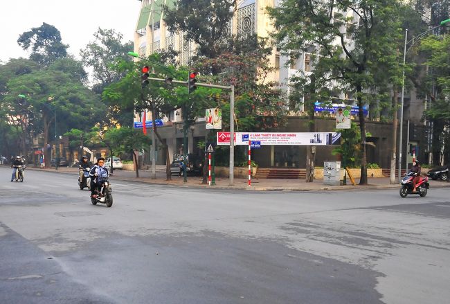 男女二人乗り、ノーヘルのバイクが、<br />赤信号を加速して直進します。