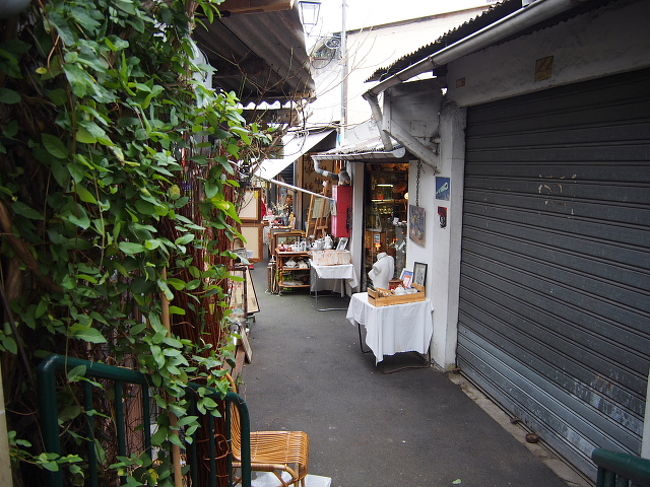地上へ出ると、空港からパリ市内へ入るときに通る、<br />高速道路の高架がある方、その向こうに並ぶテント・・・・。<br /><br />アジアの夜市のごとく、並ぶ衣料・生活雑貨なテントをやり過ごし<br />いったいドコに行けば、「蚤の市」に行けるんだ？と<br />通り沿いを歩いていると、ふと路地を見つける。<br /><br />なるほど！テントの向こうのブロックが、全部蚤の市なんだ！