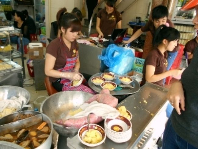 地元の人で何やらにぎわう店があったので<br />近寄ってみると、何やら黄色いものを<br />さかんに詰めては、テイクアウトしてもらってます。<br /><br />お姉さんに聞いたら、おこわだって。<br />でも、その上に豆をつぶしたものをトッピング。<br />それが基本みたい。<br /><br />さらに客の要望に応じて<br />肉や卵を乗せてくれるようです。