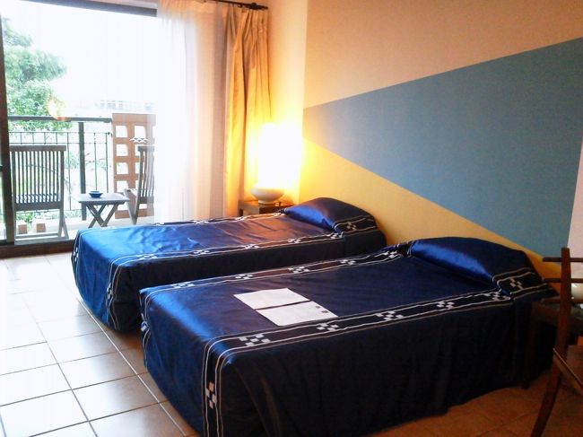 随分廊下を歩いて、ようやく部屋に着きました。案内してくれたねーちゃんを追い払い、ほっと一息。<br />ツインのスタンダードルーム(正しい名前はスーペリアルーム)です。<br />さっき観光バスで行ったみねや工房で見た、ミンサー織の柄のベッドカバー（柄が似せてあるだけで実際はポリエステル素材）が掛かっていました。