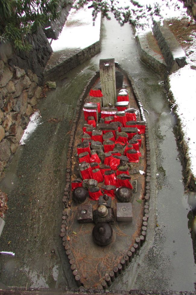 猿沢池のすぐ脇を流れる率川。<br /><br />川の中州の舟型の台座に集められた何体もの石仏。<br />この小舟はどこに流れていくのだろうか。<br /><br />石仏の赤い前掛けがモノクロの世界のアクセント。