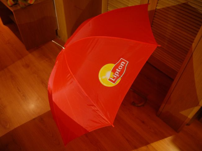 昨日バスツアーの時にバスの中に傘を置き忘れたことをホテルのフロントマンにいってツアー会社に連絡を取ってもらうようにお願いするとすぐ近くにそのツアー会社のオフィスがあるとのこと。<br />そこまで行くのにも傘がいるのでとりあえずホテルの傘を借りるとこんな傘が出てきた。<br />なぜにリプトン？？<br /><br />観光に行く前に教えてもらったオフィスに行くと本当にすぐ近くだった。<br />忘れ物で傘はないかと聞いてみたけど今のところないとのこと。<br />とりあえず届いたらホテルに連絡してほしいとお願いする。<br />しかしその時の反応からこれは期待薄だな…と感じた。<br />