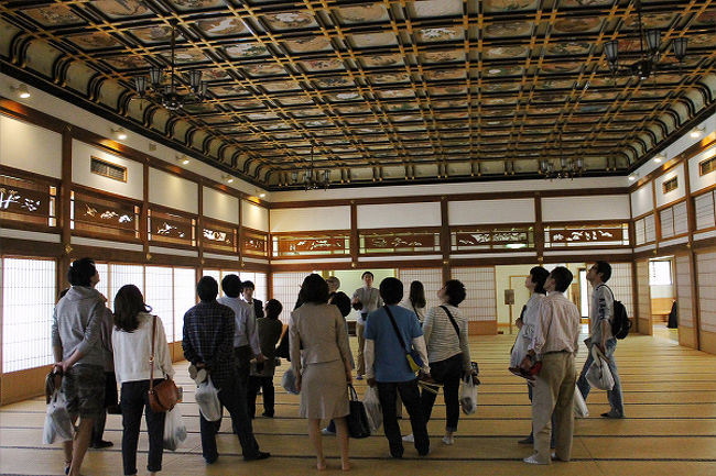 広い部屋で僧から天井画の説明を受けています。<br />この部屋は別名絵天井の大広間といわれています。<br />