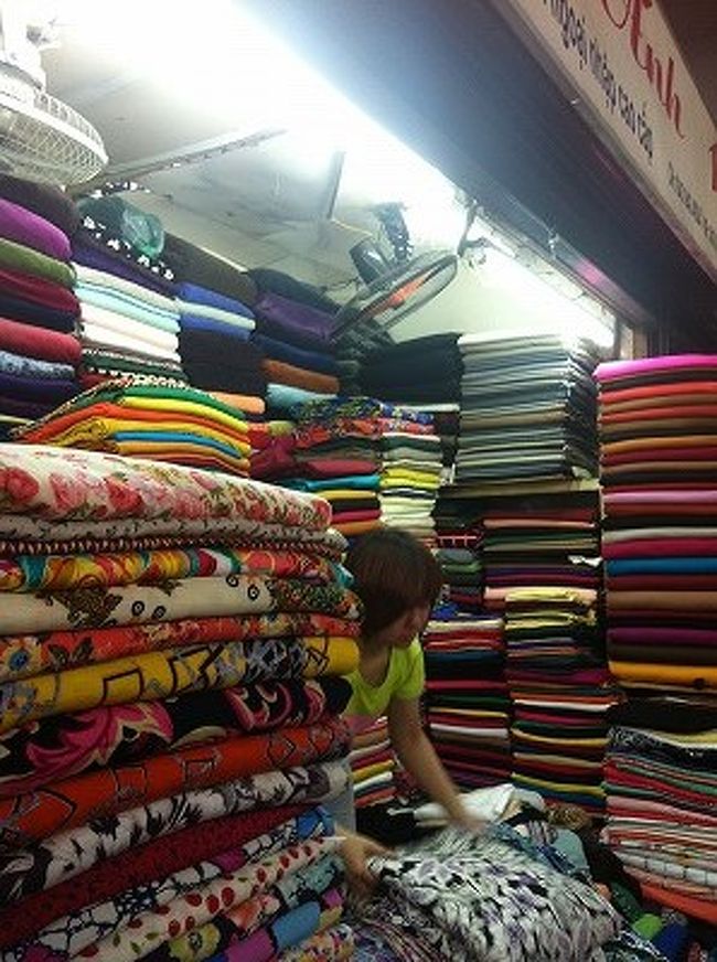 広い2階部分が布を売ってる店。<br />狭いスペースにひしめき合って並んでいる店には、お姉さんたちが座り込んで店番、というか座ってるだけの人が多い。<br /><br />化繊の生地はたくさんあるけど、コットンとなると数も少なくてデザインも好みのものがなかなかない。<br /><br />ようやく旅に便利な生地（渇きやすくて皺になりにくい）を見つけ購入。<br />1メートル20センチあればワンピース作れるという。12万ドン、600円。<br />ベトナムで仕立ててる時間はないので、ラオスでお願いしよう。