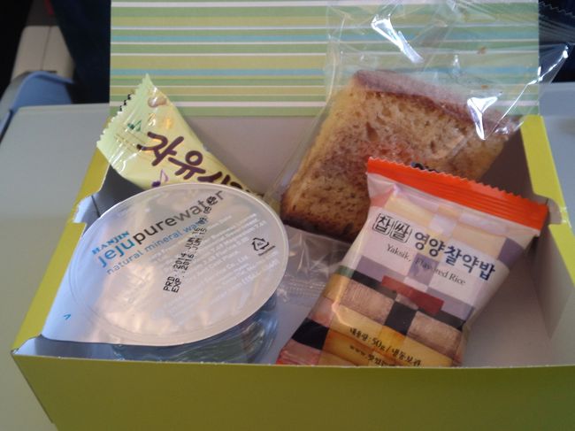 いつも変わらぬ機内食。<br />右側手前はおこわを固めたようなもの。<br />最初は味、食感ともに、なにこれ?と思いました。<br />今は、何味なのかお菓子なのか食事なのかすらわからないこの食べ物を、おいしいと感じます。<br />機内は満席で、9割方韓国人の印象です。