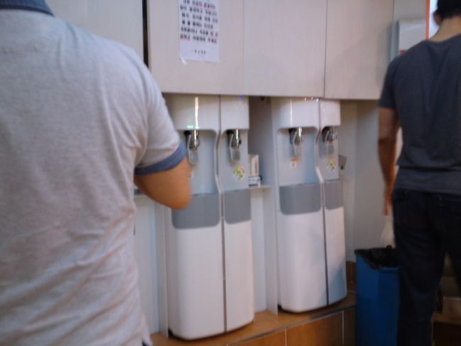 お水はベルトコンベアのそばに。<br />ペラペラの紙コップしかないので、食事しながらお水を飲むことができませんでした。<br />みんな食器を片づけたらここで水を飲み、鏡でお口チェックしてから帰っていました。