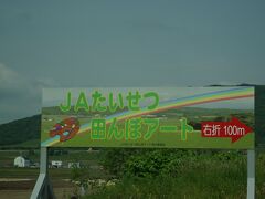 道央道の旭川北ＩＣからほど近い場所に、ＪＡたいせつ（大雪）による田んぼアートがあります。ＩＣを出てすぐに案内板が出ているので、場所は田んぼだらけの目印に乏しい場所ですが、車で辿り着くことが出来ます。
後で気が付きましたが、道央道から、この場所が見えます。アート自体はちょっと見えませんが、お立ち台を遠目に見ることが出来ました。