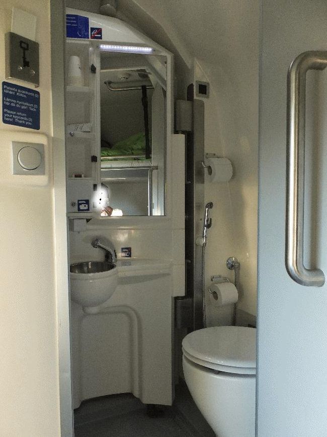　指定された部屋へ向かったが、鍵が閉まっていてドアが開かない。ホームへ出て数両分歩いて車掌のいる所へ行き、「予約があるが、私の部屋が開かない」と言うと、手元にある予約一覧の紙を確認して、「他の客がすでにいるから」ということで、部屋まで来て鍵を開けてくれた。<br />　室内の雰囲気は、ノルウェーで乗車した寝台列車となんとなく似ていた。無料のペットボトルの水も置いてある。様々な面において非常に機能的に出来ているが、欲を言えば窓と机をもう少し大きくしてほしいところである。<br />　まずは、せっかくなので軽くシャワーを浴びることにする。写真ではトイレになっているが、洗面の部分をトイレ側にぐっと引くとシャワーになるのである。<br /><br />＠上部にある禁煙マークの少し右上にシャワーが見切れている