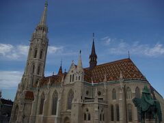 マーチャーシュ教会の全景。ハンガリーを代表する焼き物ジョルナイ製の屋根瓦が印象的です。
２年前に訪れた時は、修復中で殆ど見ることが出来ませんでした。
今回ようやくみごとな全景を見ることが出来ました。青空に良く映えます。
右手前の像がイシュトバーン王の騎馬像です。