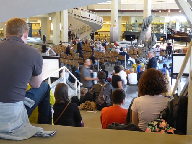 ロビーでの演奏会です。ちゃんとフルグランドがセットされております。目の前の椅子席はエリートやディスエイブルな人たちが座ります。<br />　じゃ、私たちはどうするのかといったら、床やら階段に直座りです。幸い階段の踊り場上に陣取りました。目の前は北欧から来たぴちぴちの、生意気盛りの女性４人組で、これがまたマナーが悪いんだ！たびたび係のお婆さんからちゃんと座れと怒られていますが「ふん」とかいっちゃってます。