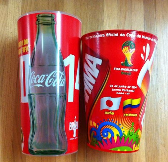 これらは、スタジアムで売られていたビール(右)と水の入っていたカップ。<br /><br />よく見ると、ビールの方は<br />その日の対戦カードの国旗と日付入りなのでお持ち帰り。<br /><br />お土産にいいかも！と思い２杯目を注文した頃には<br />国旗なしの、ただのＷ杯バージョンになっていました。ちょっと残念！<br />同じことを考える人は多いらしく<br />ビールは売れまくりでした。<br /><br />途中、夫がいないな〜と思ったら<br />しばらくの間、売場のビール注ぎを手伝わされていたそうです＾＾;<br />