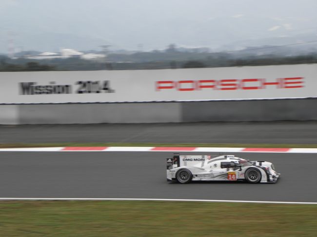 ポルシェの看板の前を走り抜けるポルシェ１４号車。