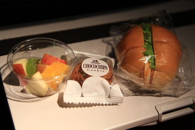 　機内食（軽食）<br />　ハムサンド、ロールパン・フルーツ・オレンジジュース・森永のクッキー
