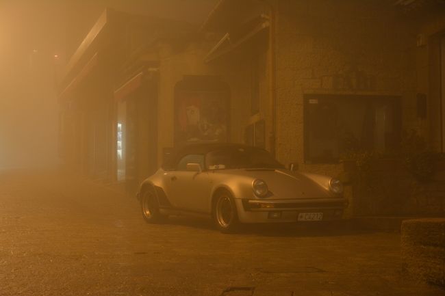 バシリカ前から伸びる道に入りつつ帰る事にしようと。<br /><br />ちょっとしたカーブを曲がった先に。<br />霧の中にポルシェが浮かび上がった。<br />