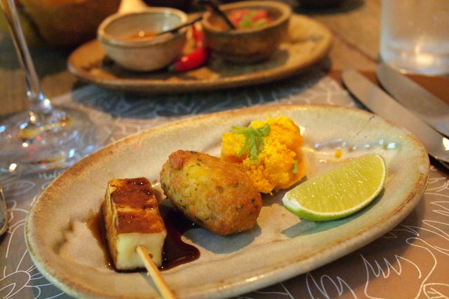 席に着くと<br />分厚いメニューを持って来てくれる<br />ページを順にめくってみると<br />かなりの種類のお料理がある<br /><br />しかしこの日は<br />最初からこれにすると決めていた<br /><br />　・MENU DEGUSTA　１５５レアル<br /><br />これはいろんな種類のお料理を<br />味わってみたいひと用のコース料理<br />ほんとはアラカルトでいろんなものを頼んで<br />シェアしたいけど、ひとりではムリ<br /><br />まず最初に供された前菜は３品盛<br /><br />　・ライスコロッケ<br />　・グリルしたチーズ<br />　・海老の練り物（のようなの）<br /><br />いずれも見かけはシンプルだけれど<br />たくさんの隠し味でとっても味わい深い