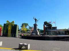 サンホセから40分ほどで、コスタリカ第2の都市 アラフェラ（Alajuela）に到着です。
コスタリカの国民的英雄 ファン・サンタマリア（Juan Santamaría）の像が見えます。
この町は彼の出生地で、彼の博物館もあります。

サンタマリアは、19世紀半ばにニカラグアがアメリカ出身の傭兵隊長ウォーカーに率いられてコスタリカに攻め込もうとした際、自らの命を投げ出してコスタリカを救った英雄です。
敵を焼き討ちにしたため、銅像の右手には松明を持っています。