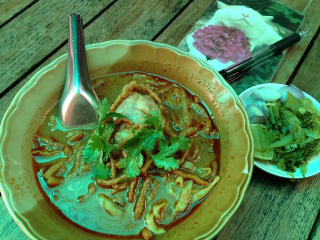 チェンマイ名物の「カオソーイ」と注文<br />付け合せに葉物野菜を醗酵させた漬物もきた<br /><br />コレはチキンのカオソーイ　　50Ｂ<br />水も注文　　　　　　　　　　10Ｂ　<br /><br />カレーのかおりもするが<br />ココナツ臭と<br />こぶみかんの葉の匂いの方が強い<br />チキンはホロホロに煮込んであって<br />口の中ですぐにほどけていく。<br /><br />唐辛子の辛さが効いてるので、水をがぶ飲み。<br />苦手なココナツ臭をトッピングのパクチーが<br />何とかごまかしてくれるのが救い<br /><br />とはいえ、パクチーもあまり好きではない<br /><br />量が少ないのが幸い<br />いちお完食したが<br />お腹は満たされない