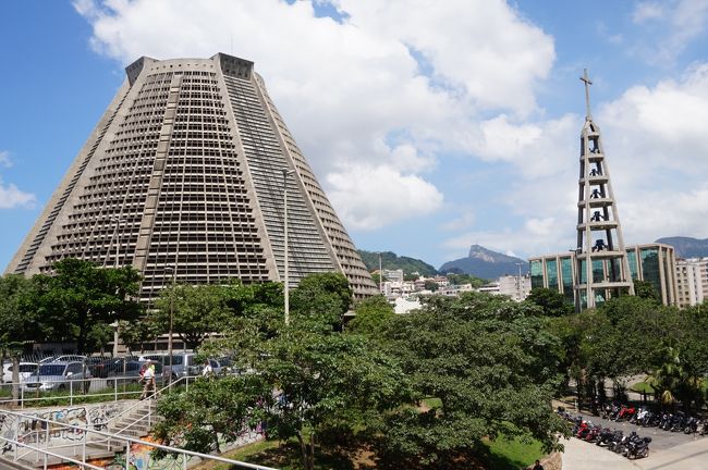 １９７６年に創建されたまだ新しい、カテドラル・メトロポリターナ(大聖堂)に来ました。ピラミッドの様な外観建物が聳えています。<br /><br />鐘楼と教会の間、奥にコルコバードの丘とその上に立つキリスト像が小さく見えています。